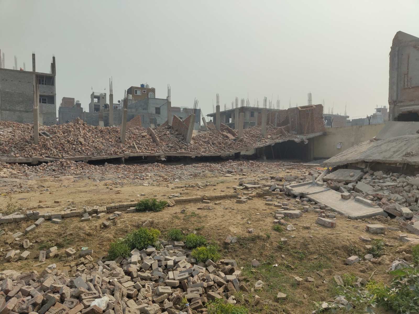 A wide plot with several flattened concrete structures and stacks of bricks