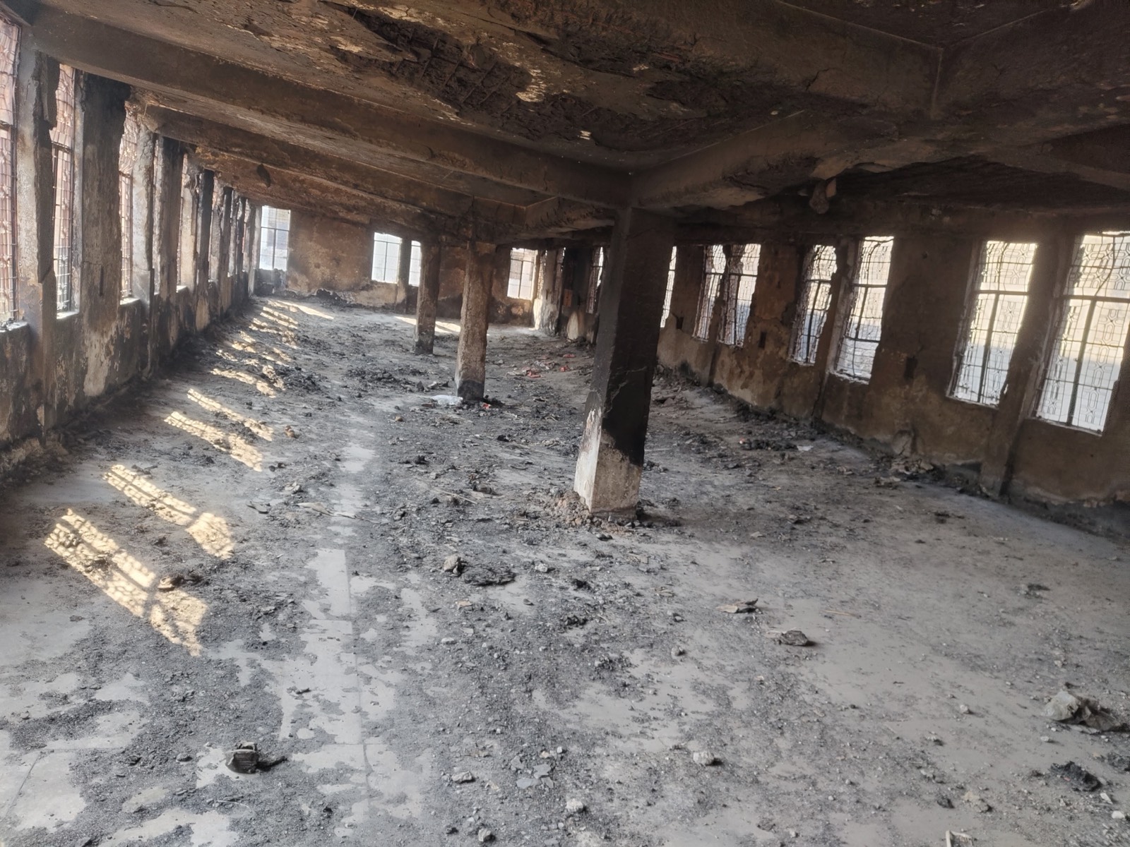 A large hall blackened by fire, with burnt columns and soot on the ceiling