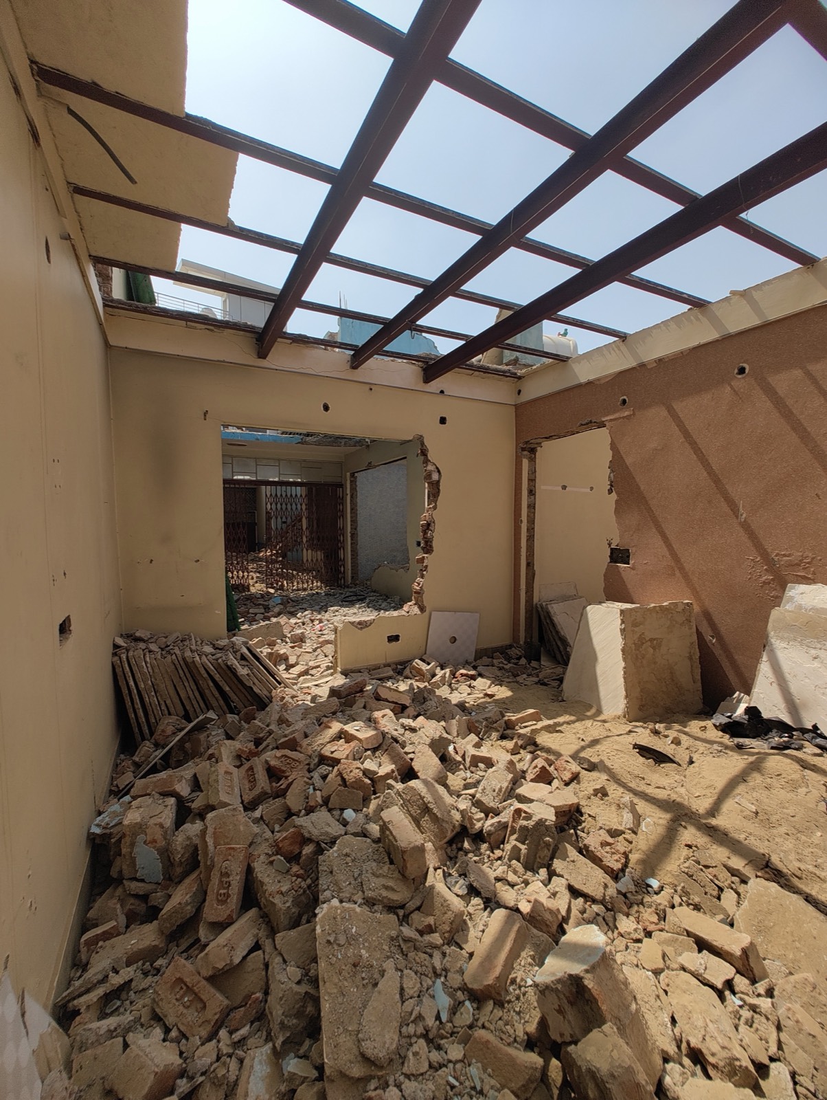 A room with its roof removed down to the steel girders, broken brick on the floor and door frames stacked to one side