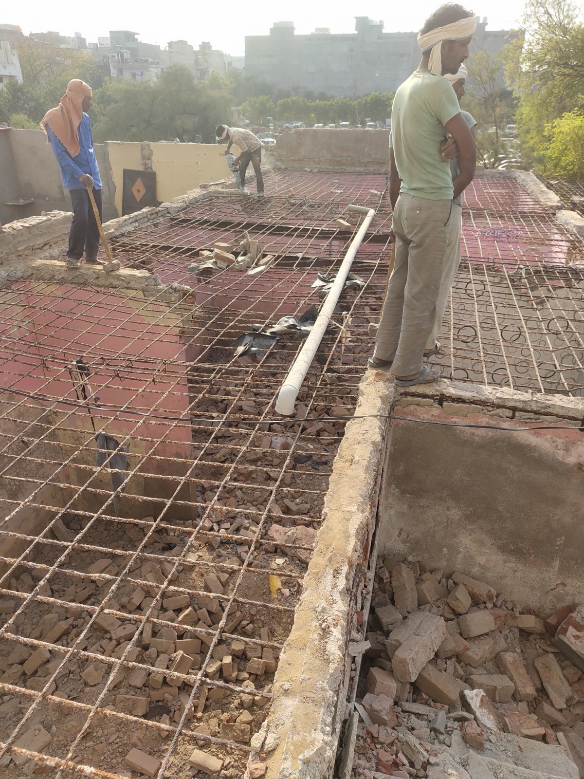 Labour team on a large roof where the concrete has been broken out, leaving the steel mesh